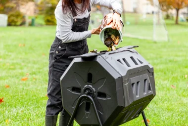 A woman loading a compost tumbler.